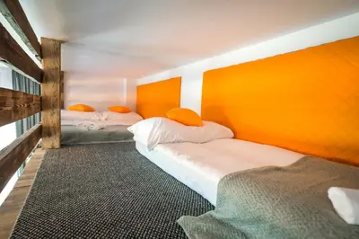 two beds in a room with an orange wall at Willa Zator in Oświęcim