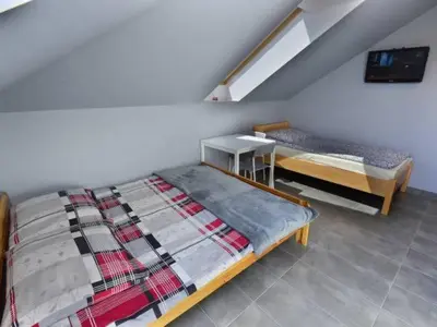 a bedroom with two beds and a table with a tv at Noclegi u Alicji in Wola Kalinowska