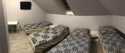 three beds in a small room with a table at Noclegi u Alicji in Wola Kalinowska