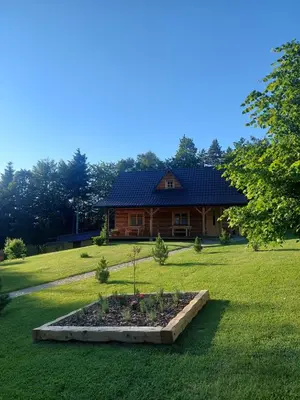 a log cabin with a slate roof on a lawn at Domek u Heli in Limanowa