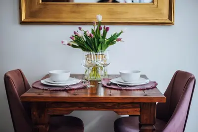a wooden table with two cups and a vase of flowers at Szpitalna 20 Apartment nr 8 in Kraków