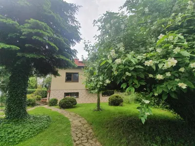 a house in the middle of a yard with trees at Gospodarstwo Agroturystyczne Borówkowy Bukiet Smaków in Iwkowa