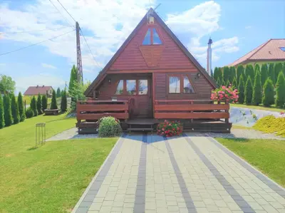 a small house with a red roof in a yard at Domek drewniany Camila in Ryczów