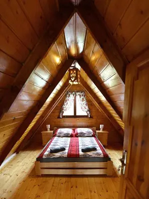 a room with a bed in a wooden attic at Domek drewniany Camila in Ryczów