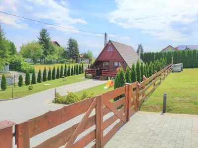 a wooden fence next to a house with a yard at Domek drewniany Camila in Ryczów