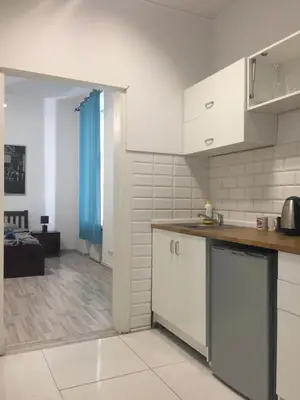 a kitchen with white cabinets and a living room at Coco apartment 1 in Kraków