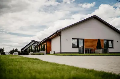 a white house with a black roof at Róża Rooms in Zator