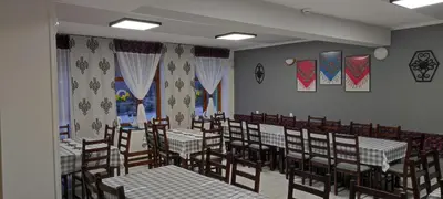 a dining room with tables and chairs and curtains at Ośrodek Wczasowy Jodła in Zawoja