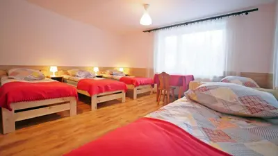 a room with four beds with red sheets and a window at Ośrodek Wczasowy Jodła in Zawoja