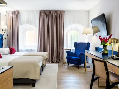 a hotel room with two beds and a desk and a blue chair at Hotel Golden Queen in Kraków