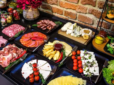 a table filled with different types of meats and cheese at Hotel Golden Queen in Kraków
