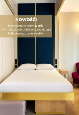 a bedroom with a bed with a blue wall at Hotel Golden Queen in Kraków