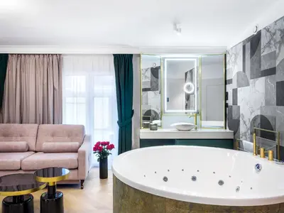 a large bathroom with a tub and a couch at Hotel Golden Queen in Kraków