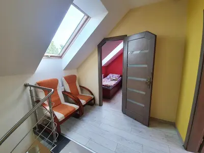a attic room with two chairs and a door at Dom nad Jeziorem Rożnowskim in Tęgoborze