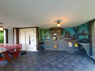 a room with a fireplace and a table and benches at Dom nad Jeziorem Rożnowskim in Tęgoborze