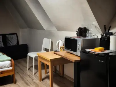 a kitchen with a table with a microwave and a refrigerator at Bracka 4 Apartament in Kraków