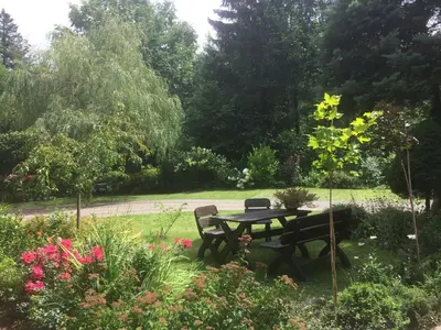 a picnic table and chairs in a garden with flowers at MARYSIEŃKA in Zawoja