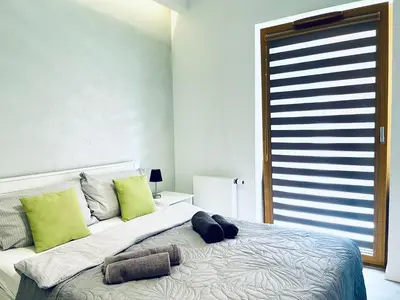 a bedroom with a bed with green pillows and a window at Modern Silver Apartment in Kraków
