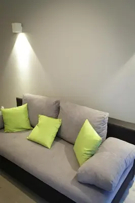 a couch with three lime green pillows on it at Modern Silver Apartment in Kraków