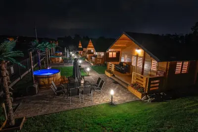 a backyard of a cabin at night with a table and chairs at Nocleg Zator Domki Paradise Pod Palmami in Zator
