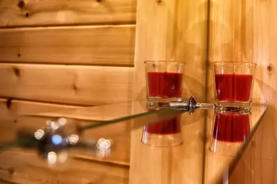 two glasses of red wine sitting on a glass table at Nocleg Zator Domki Paradise Pod Palmami in Zator