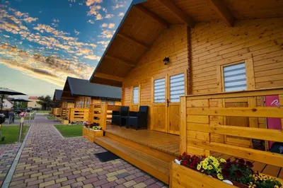 a wooden cabin with a porch and a fence at Nocleg Zator Domki Paradise Pod Palmami in Zator