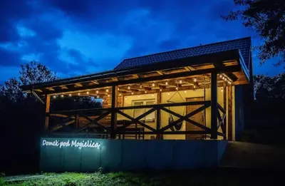 a large wooden building with a lit up facade at night at Domek pod Mogielicą in Chyszówki