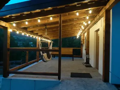 a porch with a hammock and lights on it at Domek pod Mogielicą in Chyszówki