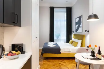 a bedroom with a bed and a table and a kitchen at Nola Apartments in Kraków
