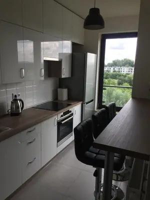 a kitchen with white cabinets and a table and a window at Apartament Kraków Arena No. 100 in Kraków