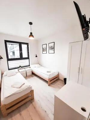 a living room with two beds and a large window at Apartament Kraków Arena No. 100 in Kraków