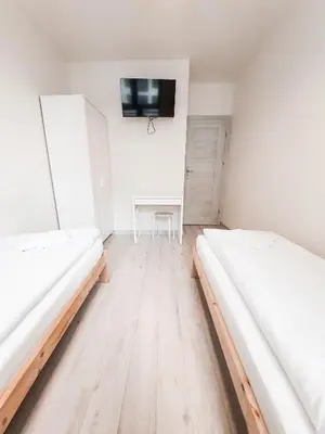 two beds in a room with a table and a tv at Apartament Kraków Arena No. 100 in Kraków