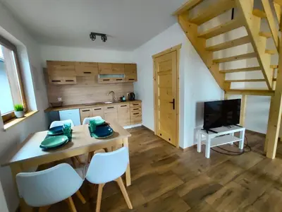 a kitchen with a wooden dining table and a television at Happy Holiday domki Zator in Zator