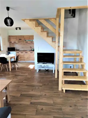 a living room with a wooden staircase and a kitchen at Happy Holiday domki Zator in Zator