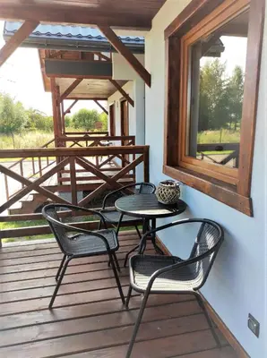 a patio with four chairs and a table on a deck at Happy Holiday domki Zator in Zator