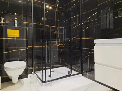 a bathroom with black tiled walls and a toilet at Cracow by Night Apartments in Kraków