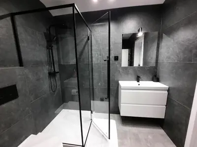 a bathroom with a glass shower and a sink at Cracow by Night Apartments in Kraków