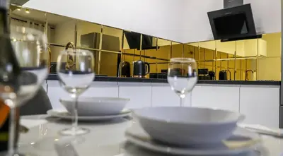 two glasses of wine on a table with plates and bowls at Cracow by Night Apartments in Kraków