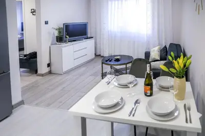 a living room with a white table and a tv at Cracow by Night Apartments in Kraków