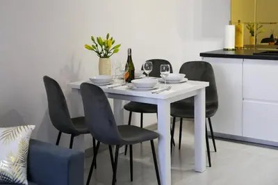 a white table with black chairs and a bottle of wine at Cracow by Night Apartments in Kraków