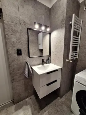 a bathroom with a white sink and a mirror at Cracow by Night Apartments in Kraków