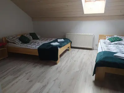 two beds in a room with wooden floors at Noclegi przy Skawie in Zator