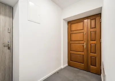 a hallway with a wooden door and white walls at NEW APARTMENT! Jewish quarter - SEGUNDO in Kraków
