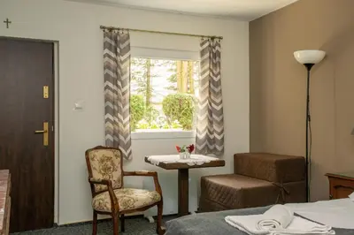 a room with a chair and a table and a window at Noclegi Pod Dębem u Jakuba in Niepołomice