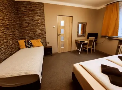a room with two beds and a table with a desk at Villa For You in Oświęcim