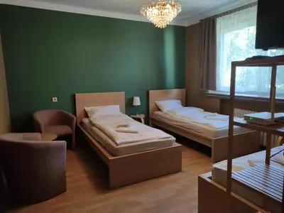 a green room with two beds and a chandelier at Villa For You in Oświęcim