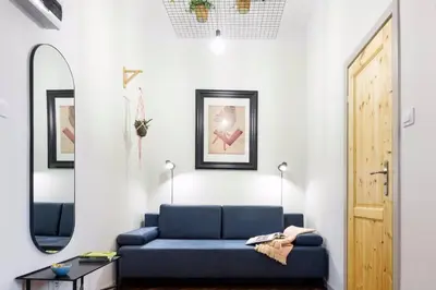 a living room with a blue couch and a mirror at Small folksy studio Kochanowskiego St in Kraków