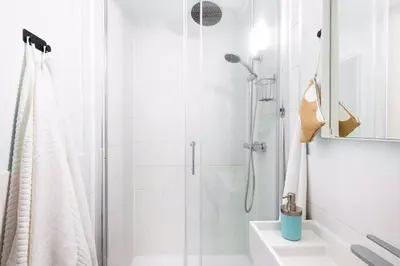 a white bathroom with a shower and a sink at Small folksy studio Kochanowskiego St in Kraków