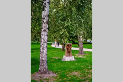 a park with trees and a statue in the grass at Small folksy studio Kochanowskiego St in Kraków