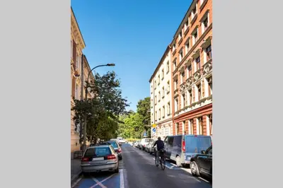 a person riding a bike down a street with parked cars at Small folksy studio Kochanowskiego St in Kraków